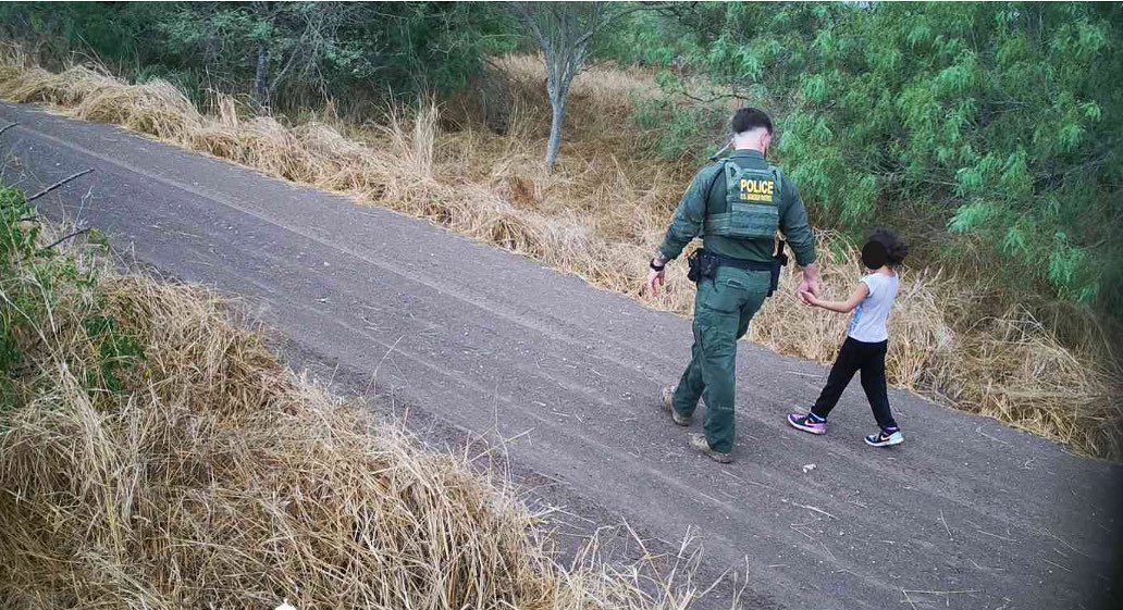 Un agente de la Patrulla Fronteriza en el Condado Hidalgo lleva de la mano a una niña migrante abandonada por el contrabandista muy cerca del Rio Bravo (foto Border Patrol RGV )